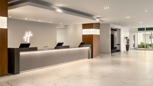 Un comptoir d’accueil moderne au design minimaliste, un sol impeccable et un grand panneau lumineux.