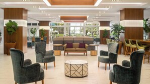 Un hall d’entrée avec un canapé, des fauteuils, une table basse et une grande fenêtre.