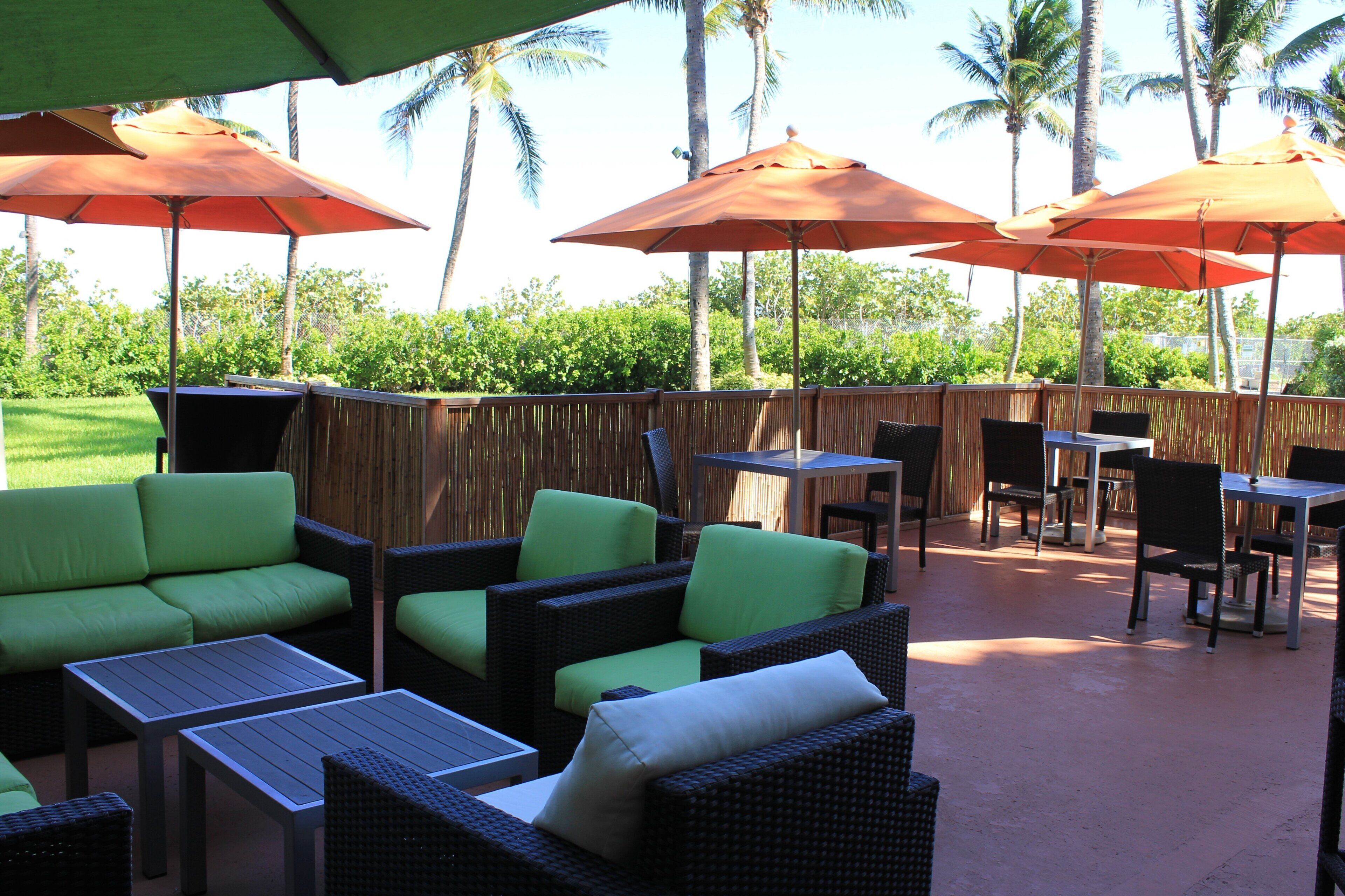 Un espace extérieur aménagé en terrasse, avec des meubles en osier, des tables et des parasols.