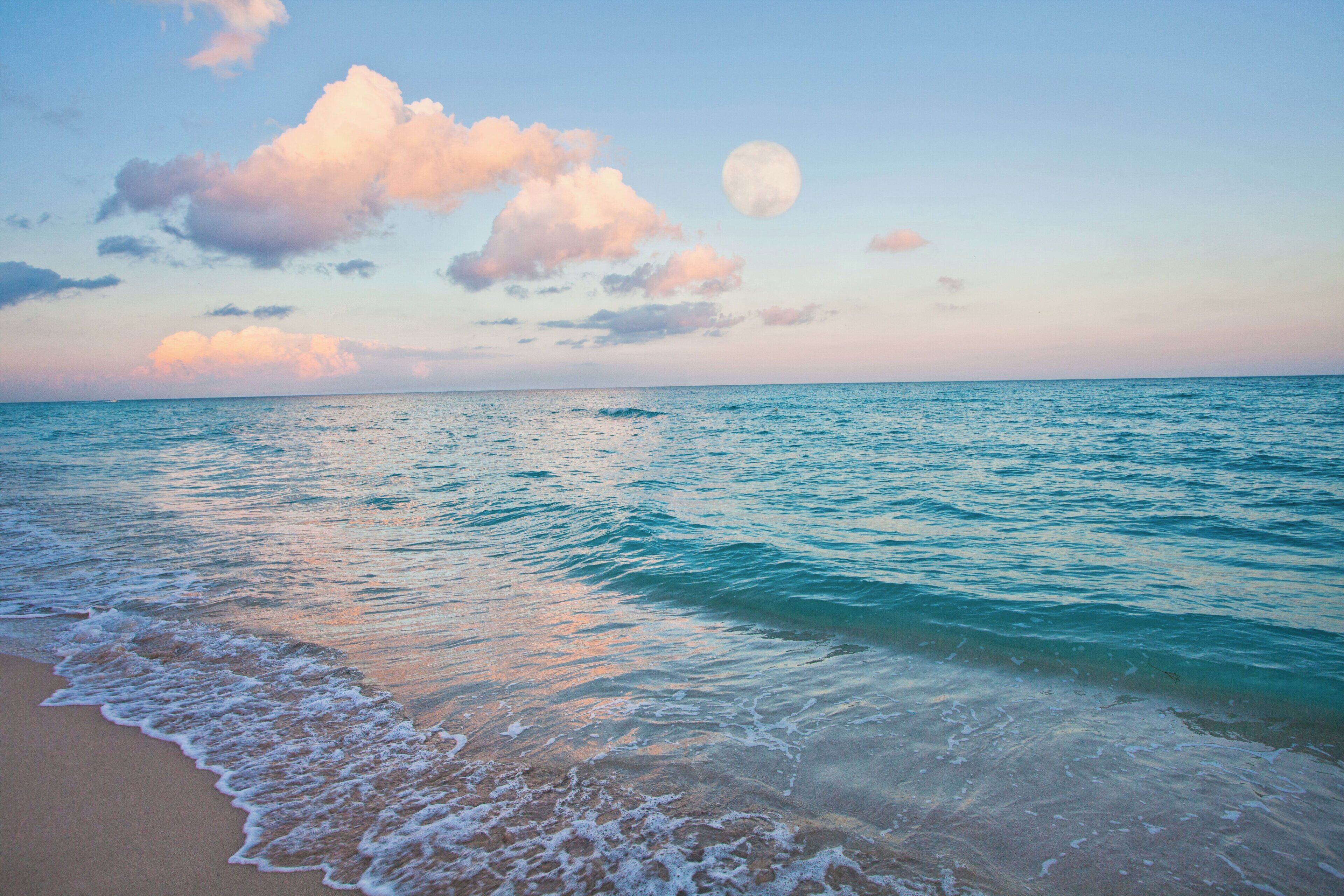 A beach with waves gently lapping onto the shore and a clear sky above.