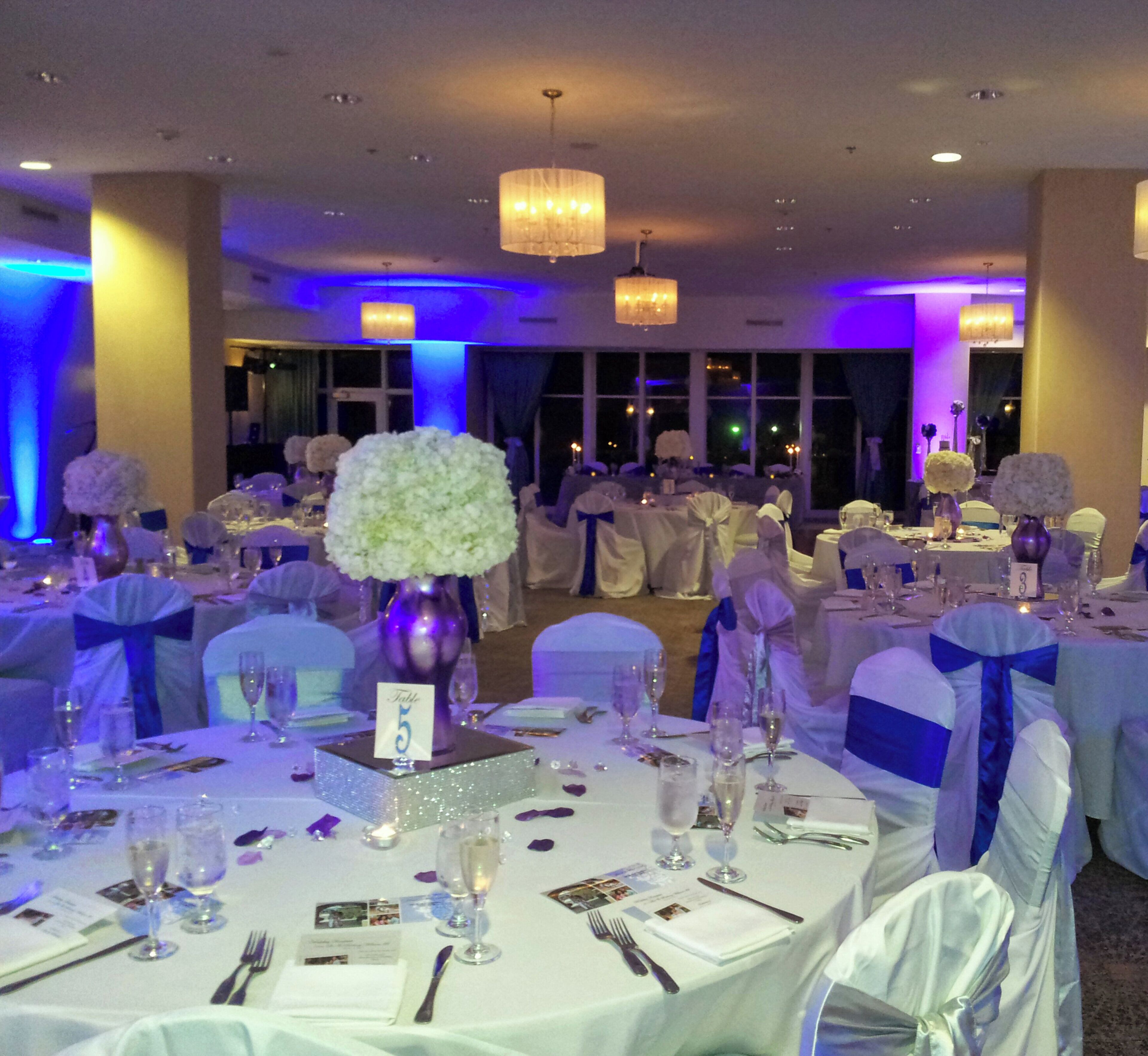 A banquet hall with round tables, white tablecloths, and blue sashes.