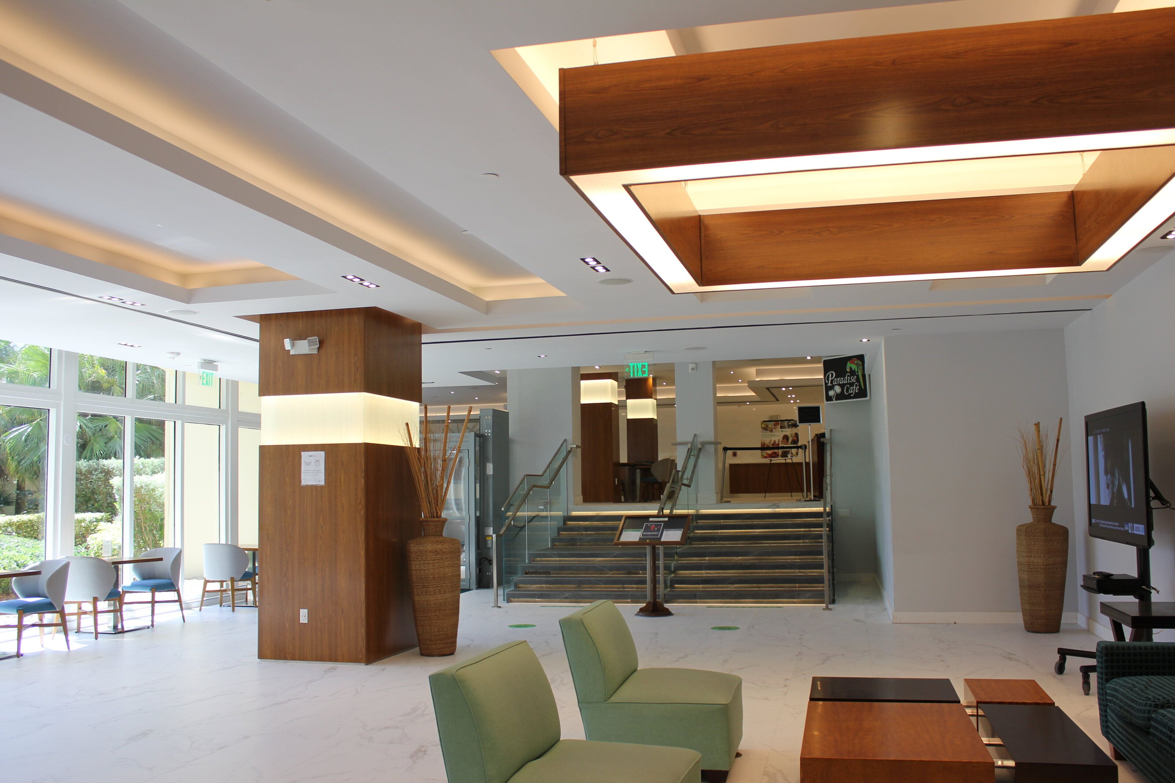 A modern lobby with a reception desk, seating area, and a staircase leading to an upper level.