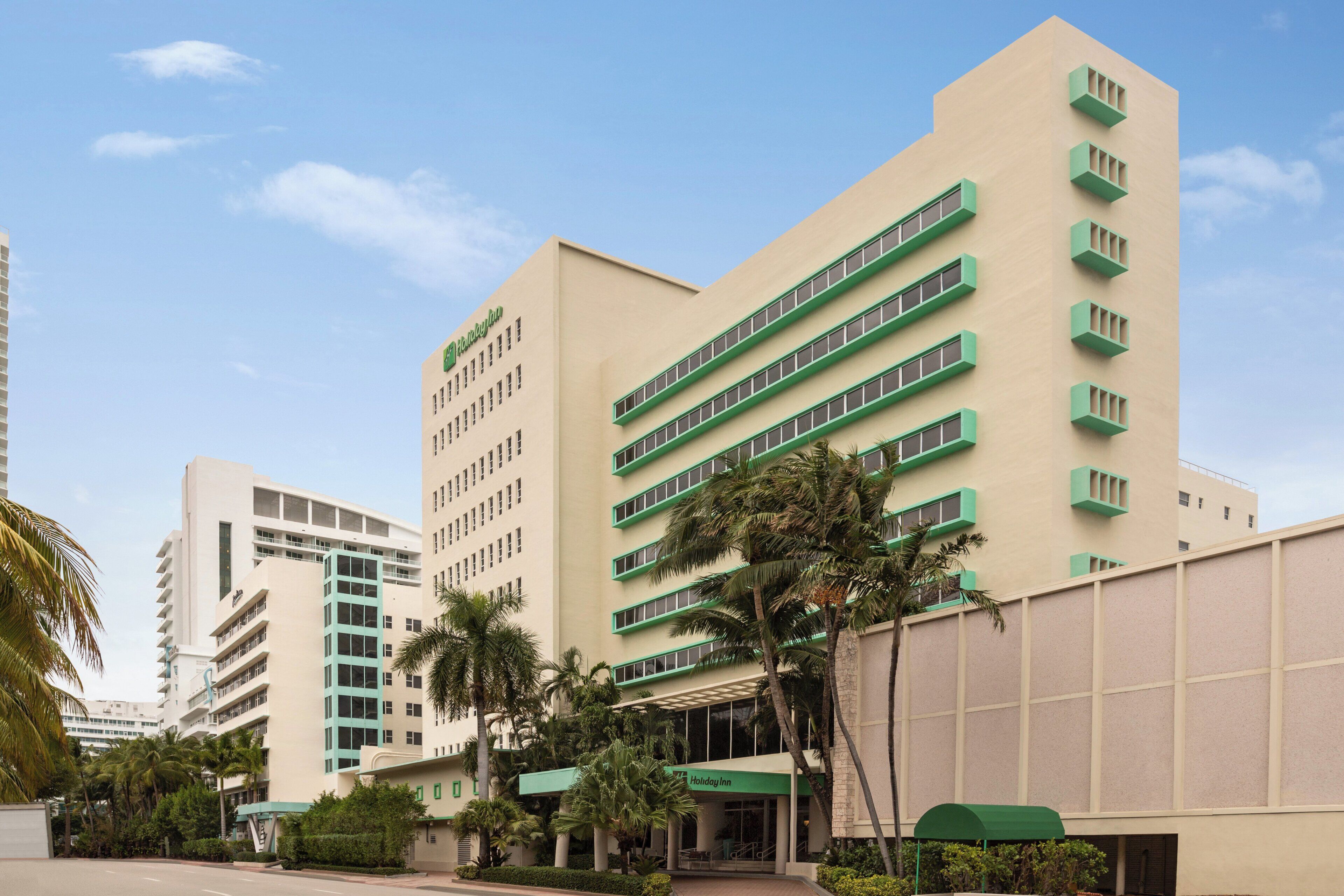 Un immeuble à plusieurs étages, doté d’un auvent vert et d’une enseigne indiquant « Holiday Inn ».
