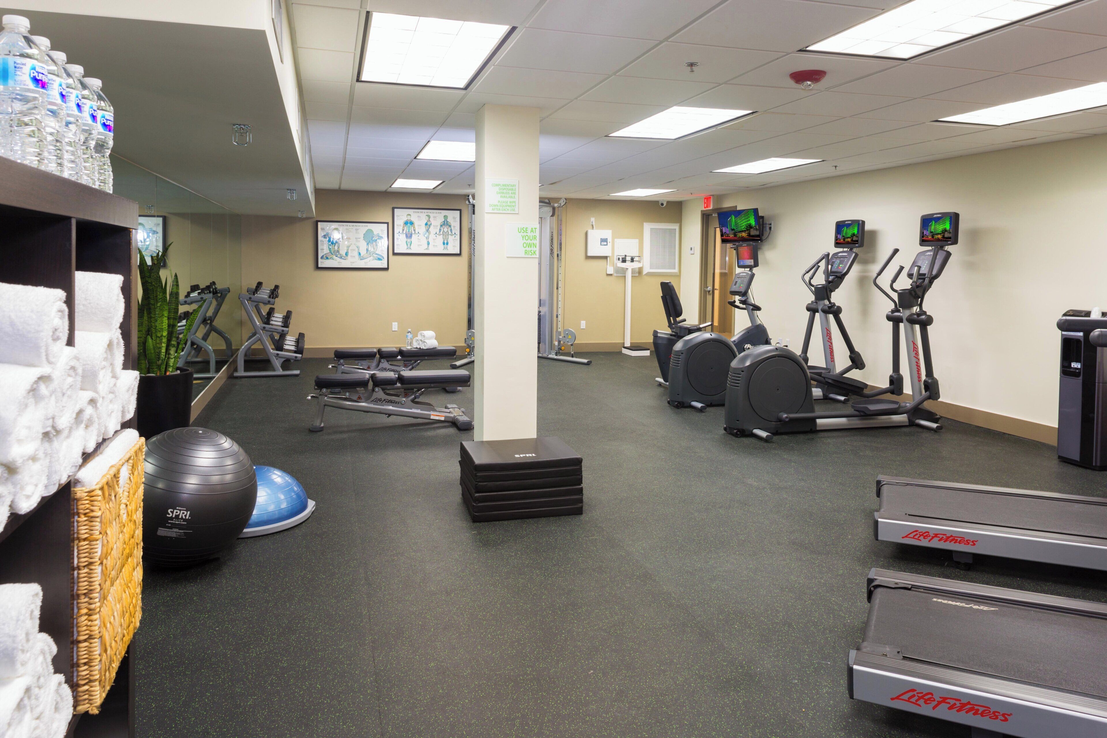 A gym with exercise equipment, a water dispenser, and a wall-mounted television.