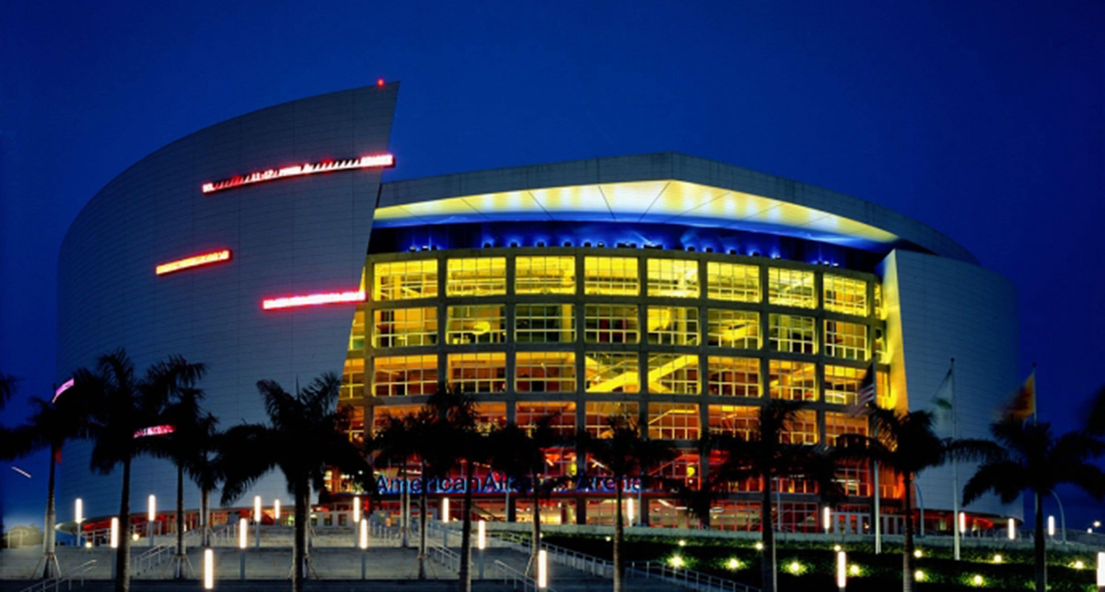 A modern building with a curved facade, large windows, and a well-lit entrance area with palm trees.