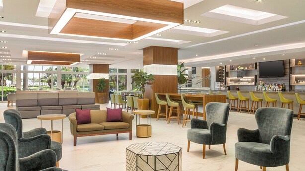 Un hall d’hôtel moderne doté d’espaces de détente, d’un bar et d’un téléviseur.