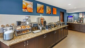 A breakfast bar with various food items, a coffee machine, and a refrigerator.