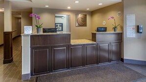 A hotel reception desk with a check-in counter, a Dell computer, and a potted orchid.