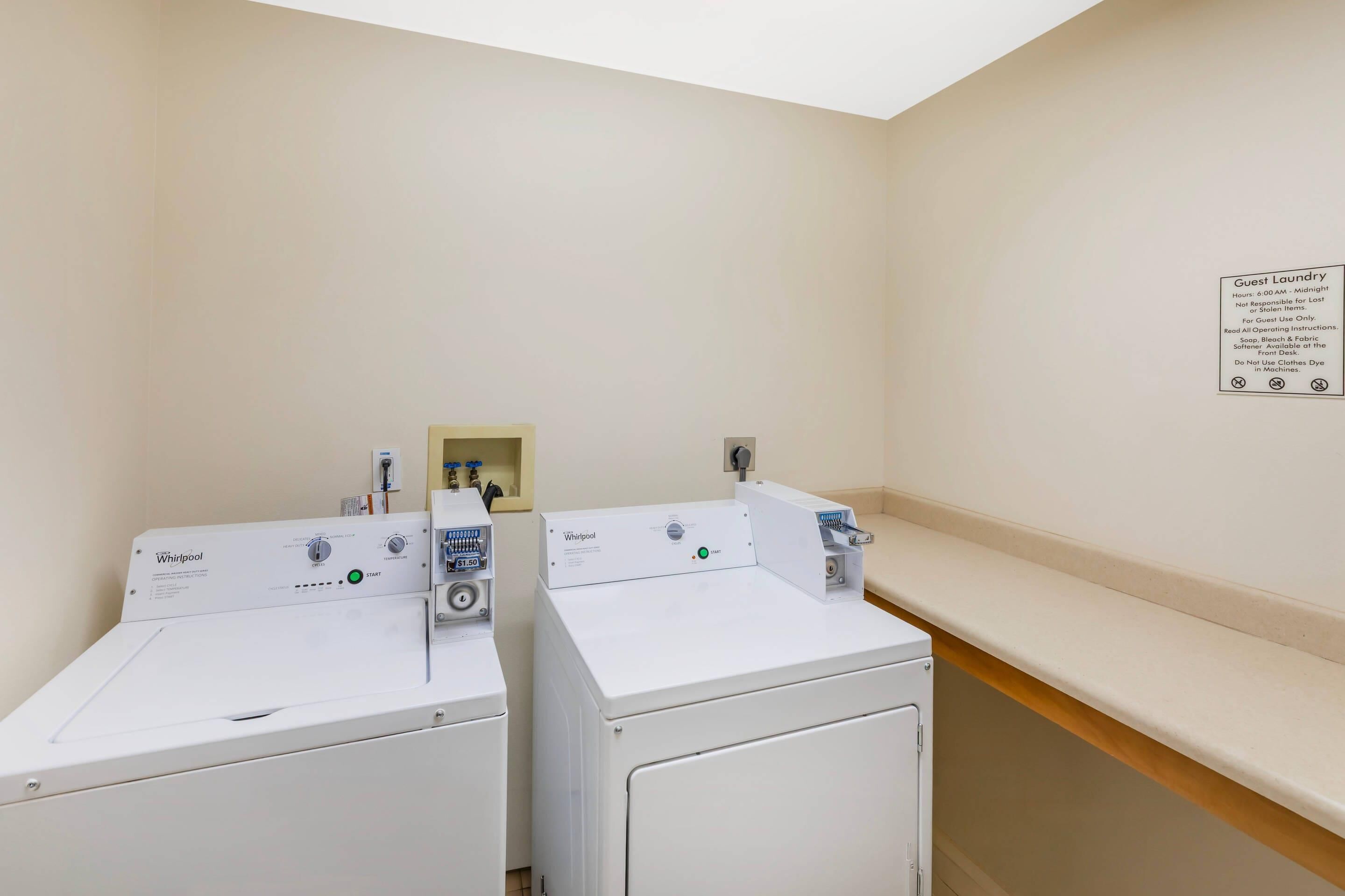 Un área de lavandería con dos lavadoras Whirlpool y un cartel que detalla las normas para huéspedes.