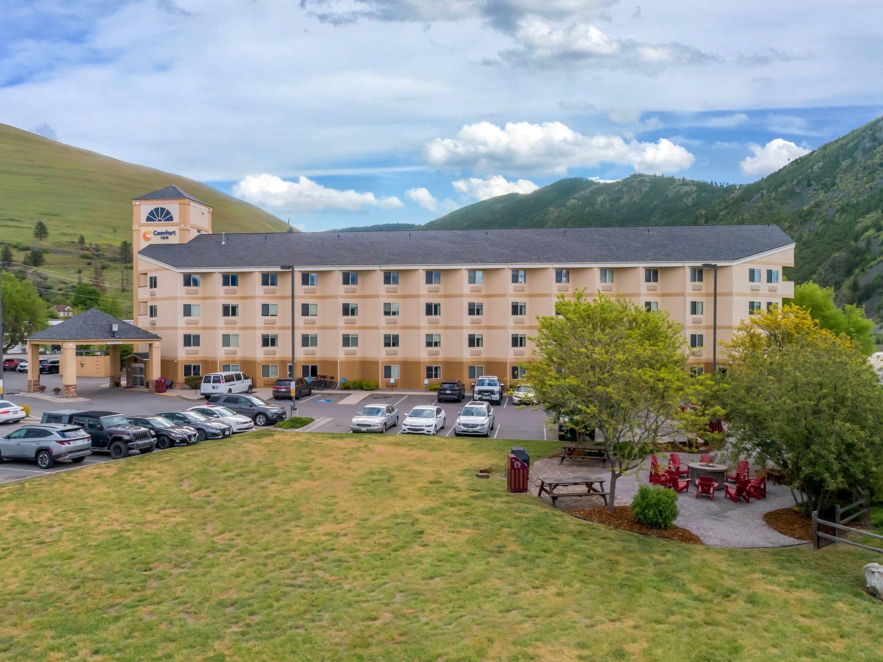 Un hôtel à plusieurs étages doté d’un parking, d’une entrée couverte et offrant une vue sur les collines environnantes.