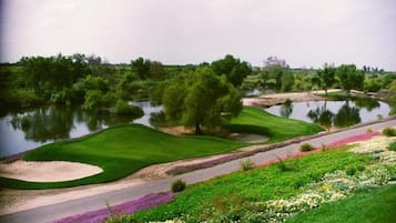 A golf course with a water hazard, sand bunkers, and a well-maintained lawn.