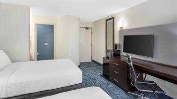 Une chambre d’hôtel avec deux lits, un bureau avec une chaise, une télévision et un miroir.
