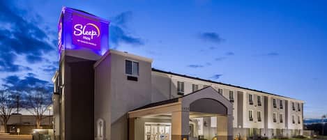 A Sleep Inn by Choice Hotels building with a covered entrance and a parking lot.