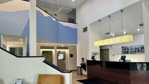 A hotel reception area with a modern design, including a reception desk, a seating area with a chair, and a staircase leading to an upper level. - Sleep Inn Missoula Southgate (Missoula)