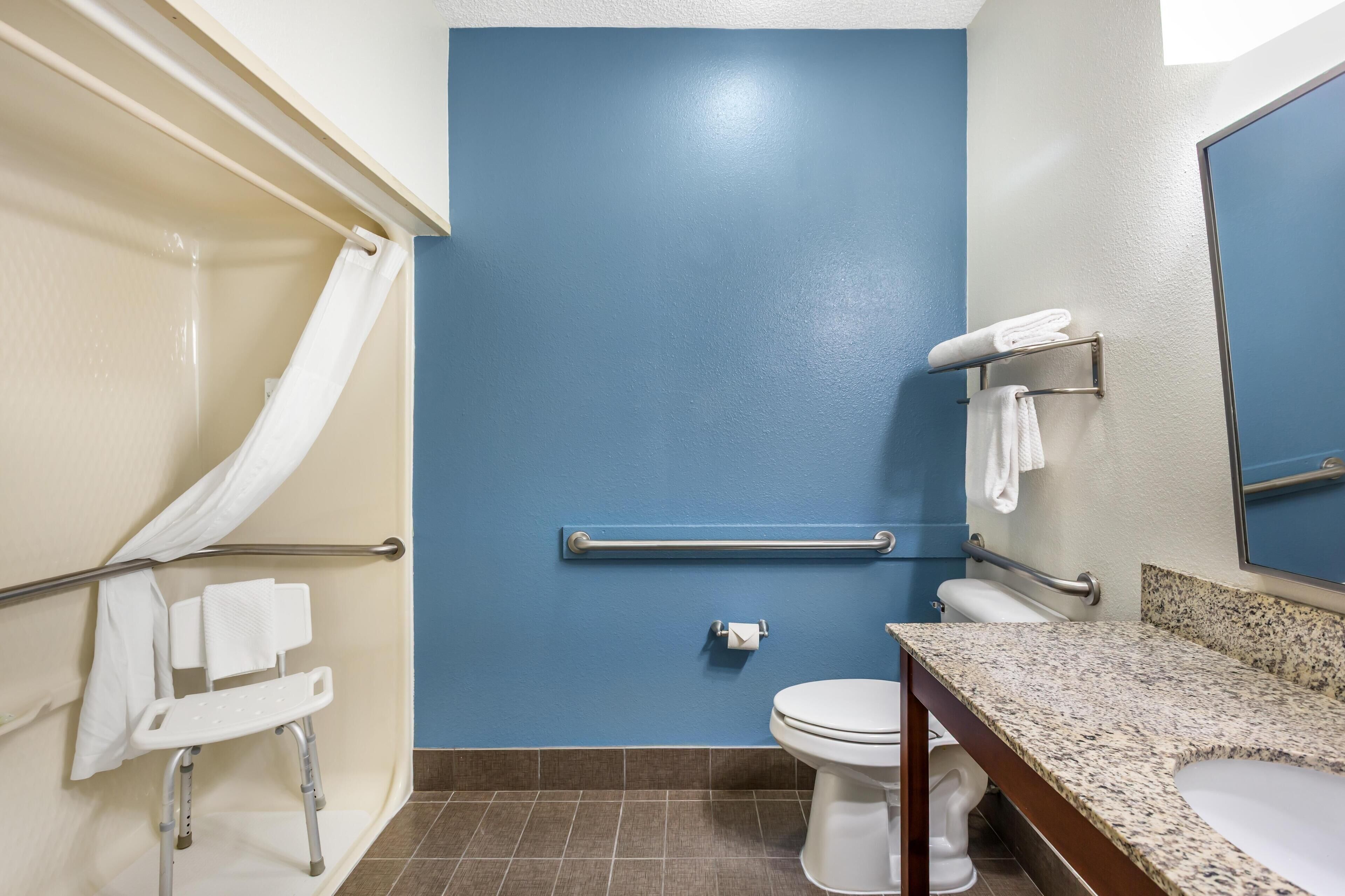Een badkamer met een blauwe wand, een wit toilet, een granieten aanrechtblad en een douchehoek met een wit gordijn.