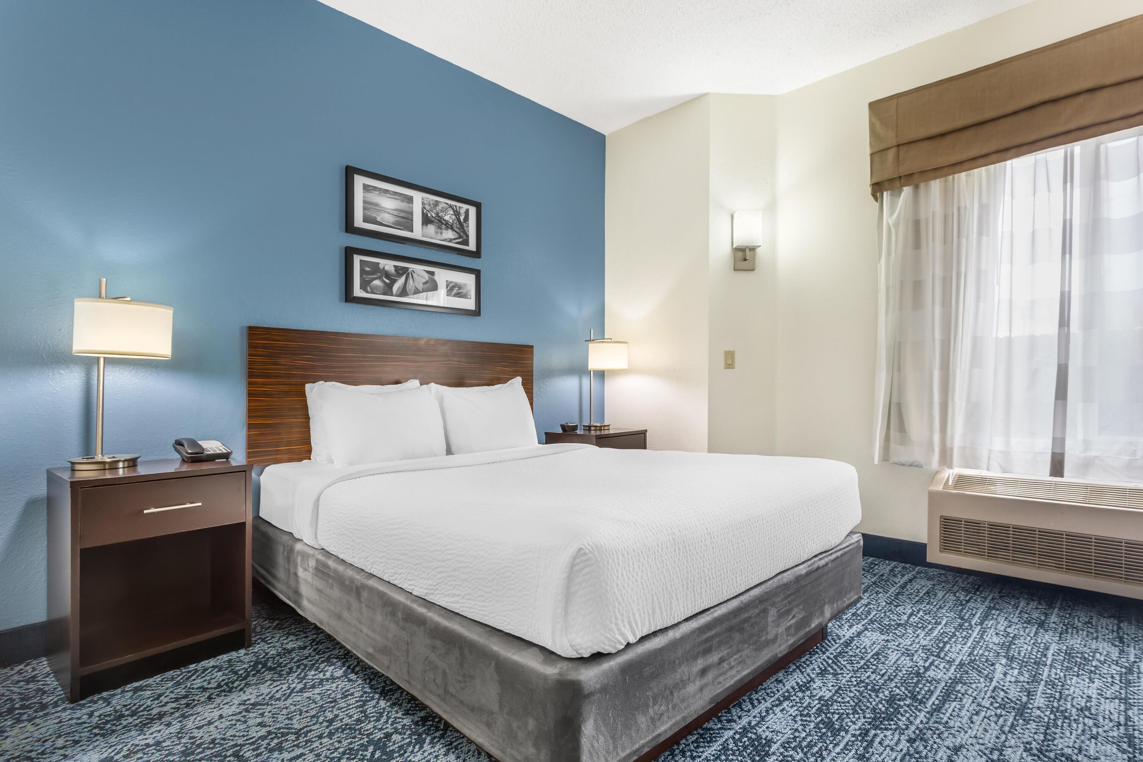 A hotel room with a large bed, two bedside tables with lamps, a wall-mounted phone, and two framed pictures.