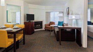 Habitación de hotel con comedor, sofá, televisor, chimenea y lámpara.