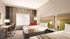 Habitación de hotel con dos camas, un escritorio, una silla y una ventana con cortinas.