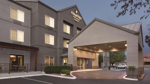 Un hotel moderno con techo plano, entrada cubierta y estacionamiento.