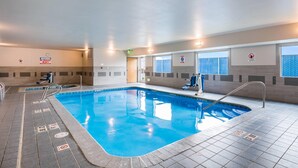 An indoor swimming pool with clear signage, tiled flooring, and a view of the outside through large windows.