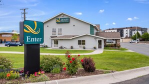A Quality Inn & Suites hotel with a signboard, a well-maintained lawn, and a parking area.