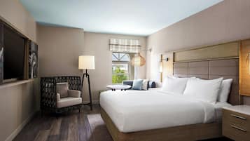 A modern hotel room with a large bed, a small table, a chair, and a TV.