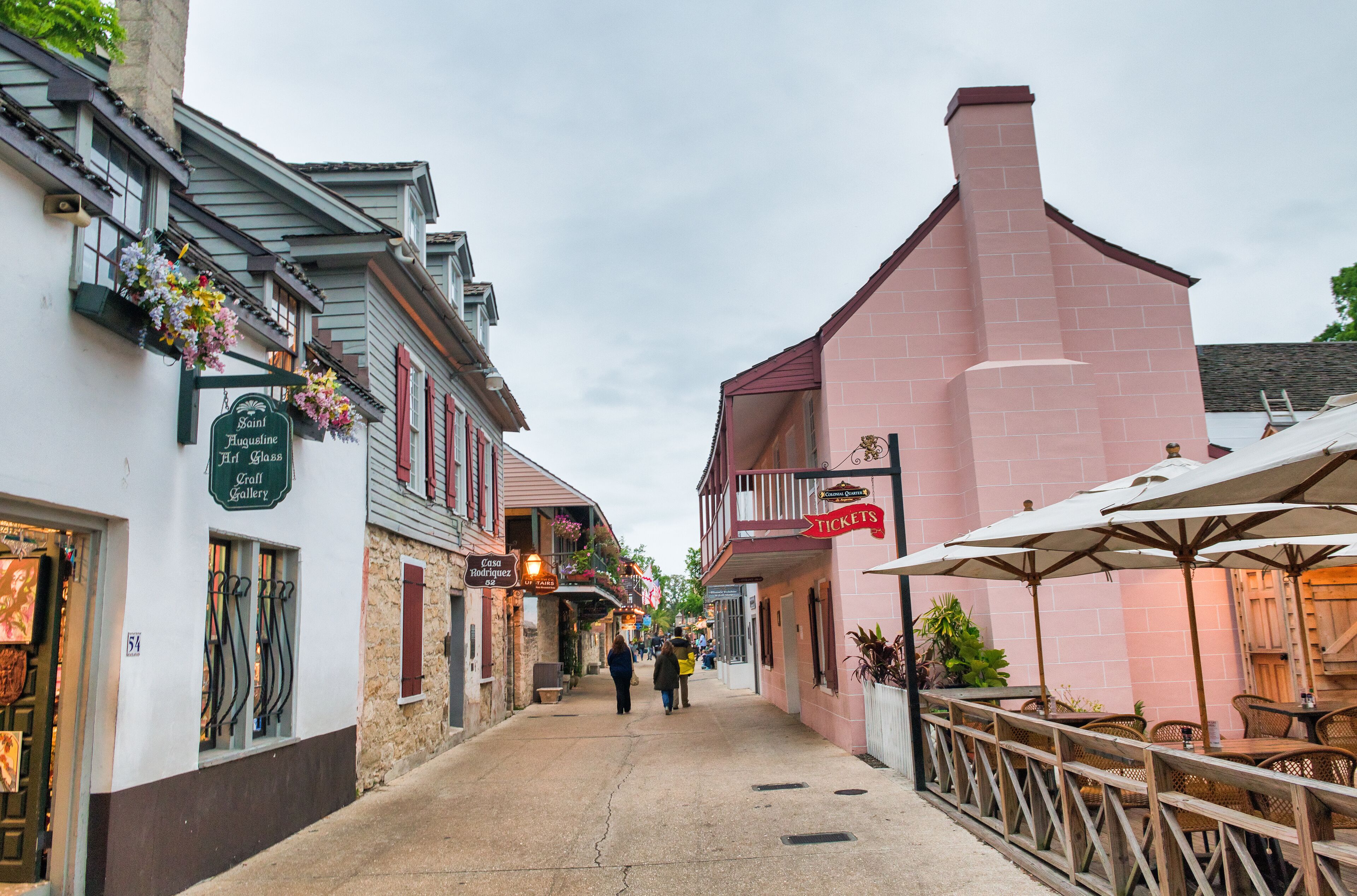 Une rue étroite bordée d’immeubles, dont une galerie d’art et un restaurant doté d’une terrasse.