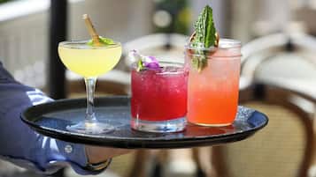 Three drinks on a tray with a person holding it.