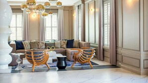 Een ruime woonkamer met een grote bank, twee gestreepte fauteuils, een bijzettafeltje en een decoratieve vloerlamp.