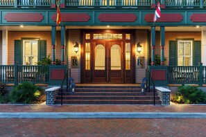 Ein Hotel, dessen Eingang eine hölzerne Doppeltür mit zwei Stufen und an jeder Seite eine rot-weiße Flagge zeigt.