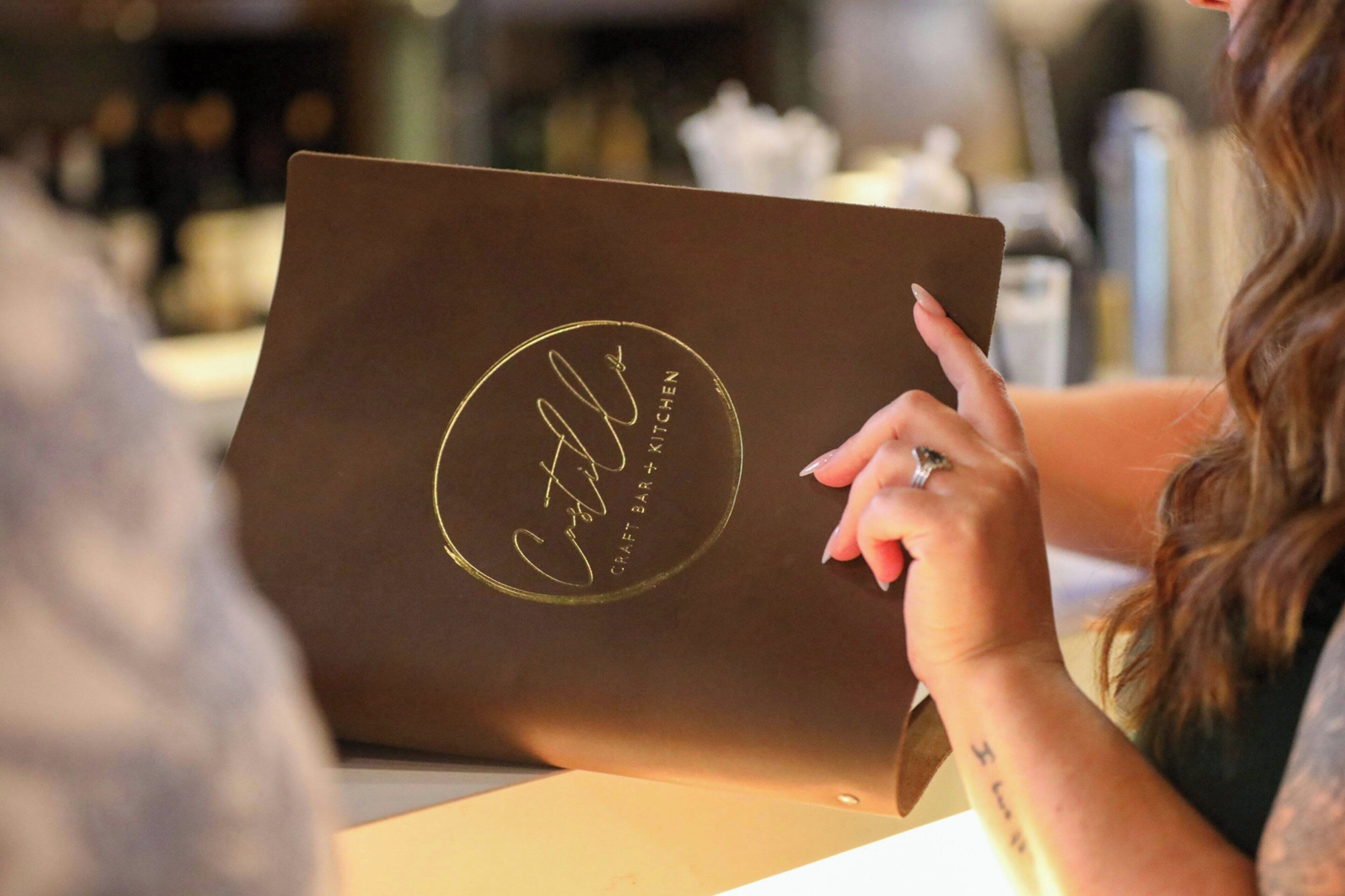 A person using a laptop with a logo on the lid.