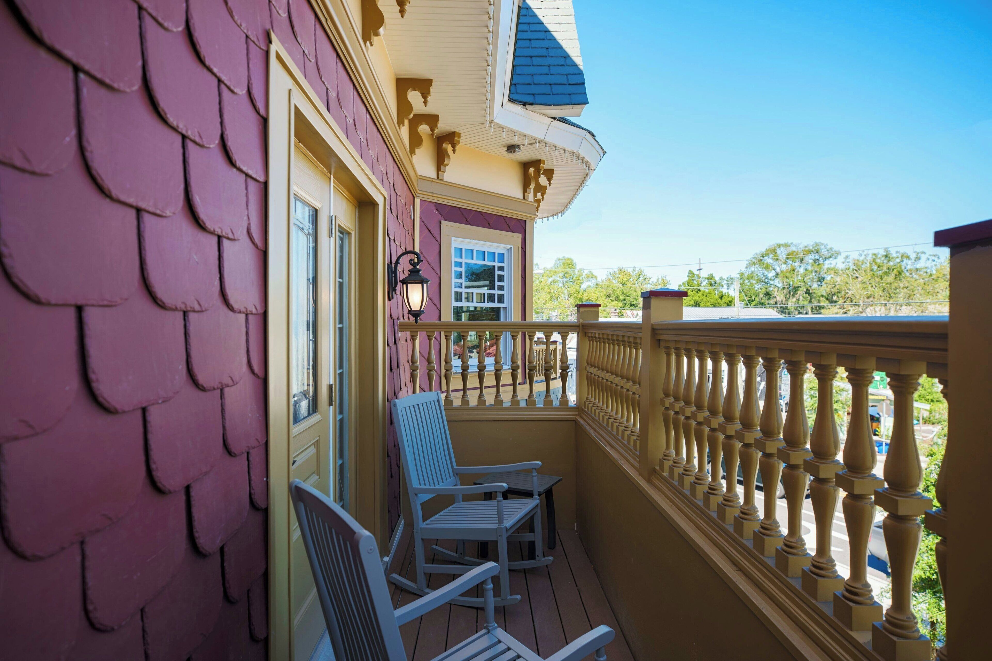 Un balcon agrémenté d’une balustrade décorative, d’une chaise berçante et d’une chaise.