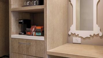 A modern bathroom with a wooden vanity, a mirror with an ornate frame, and a beige bench.