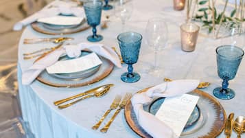A table set with blue glassware, gold cutlery, and a menu card.