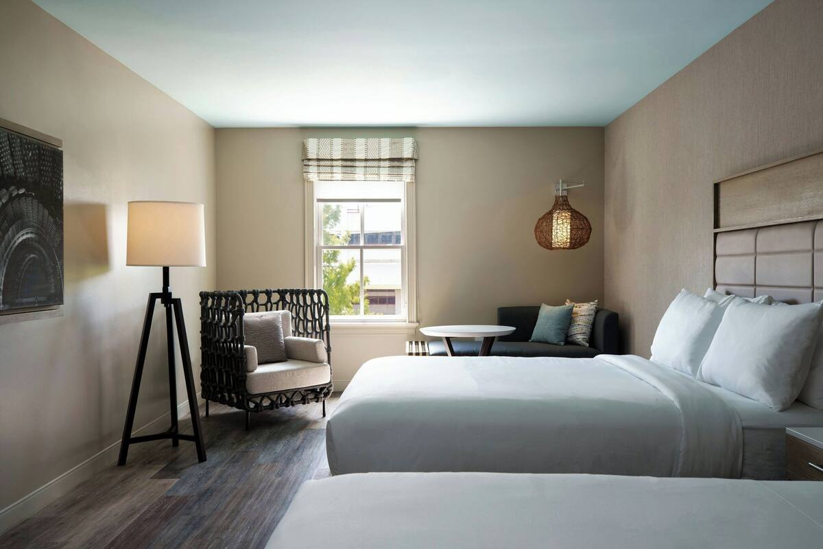 A hotel room with a large bed, a small table, a chair, and a lamp.