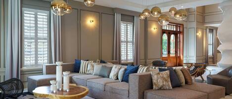 A spacious living room with a large beige sectional sofa, multiple hanging spherical light fixtures, and a round wooden coffee table.