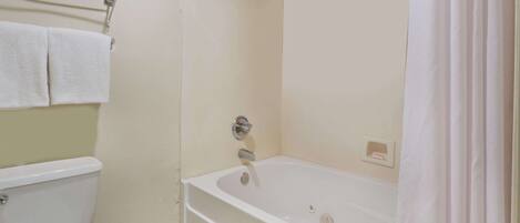 A bathroom with a toilet, a bathtub, and a shower curtain.