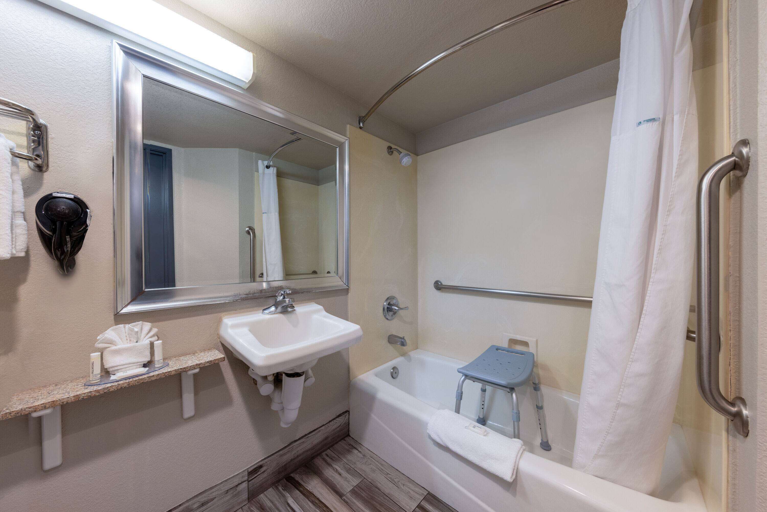 A bathroom with a sink, mirror, bathtub, and a shower curtain.
