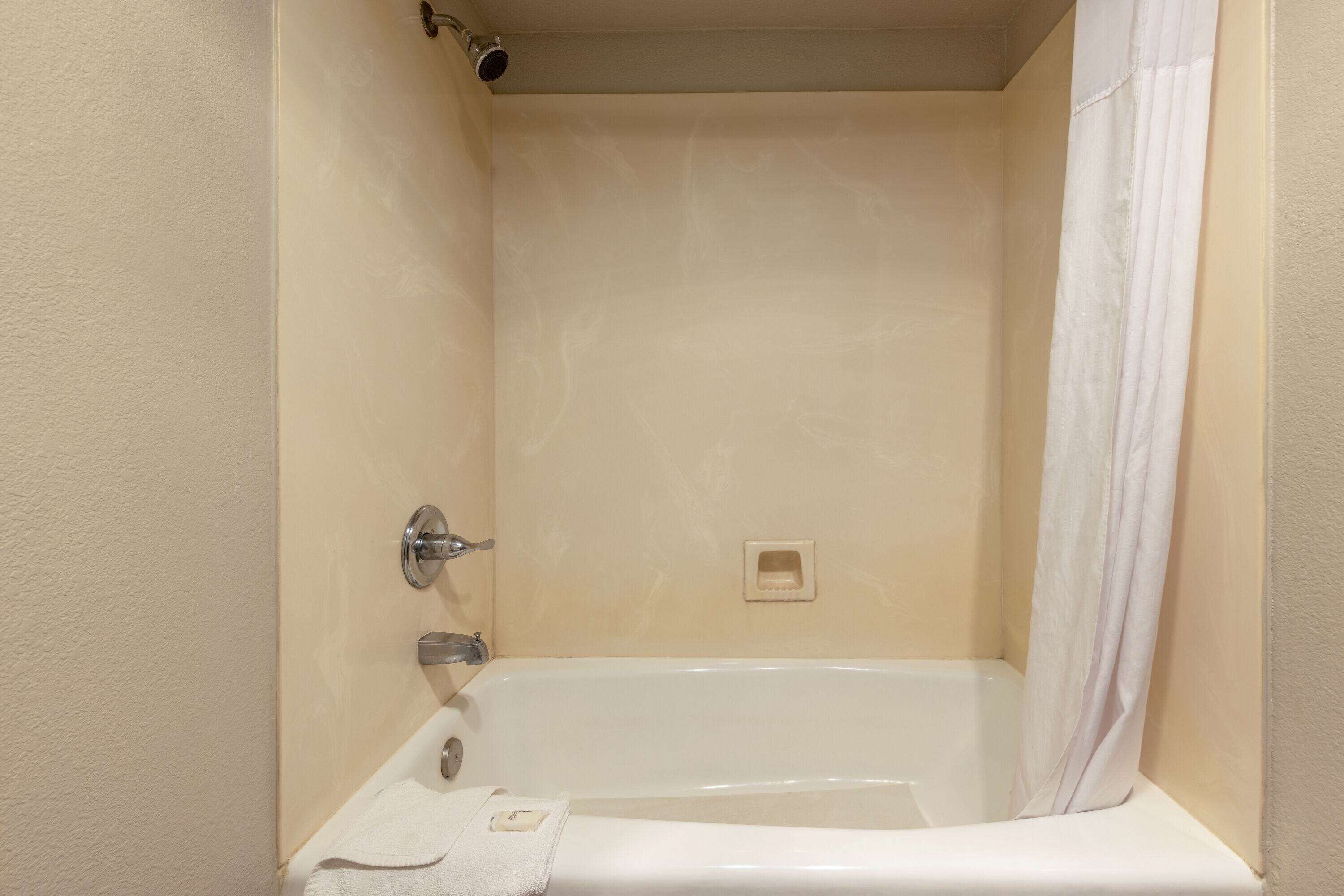Un baño con bañera, cortina de ducha y toalla.