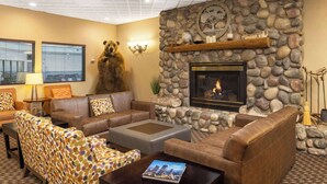 A cozy living room with a stone fireplace, leather sofas, and a bear statue. - Hampton Inn Kalispell (Kalispell)