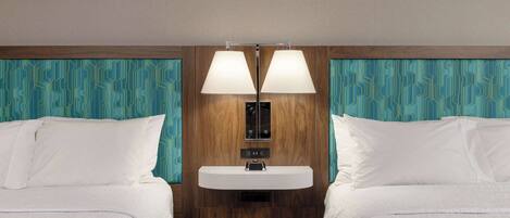 A hotel room with two beds, a built-in sink, and a mirror above it.