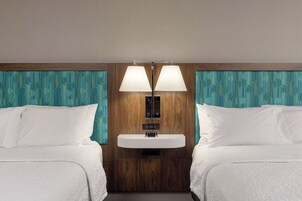 Habitación de hotel con dos camas, un lavamanos incorporado y un espejo encima.