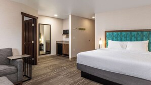 A hotel room with a bed, a seating area, a desk, and a mirror. - Hampton Inn Kalispell (Kalispell)