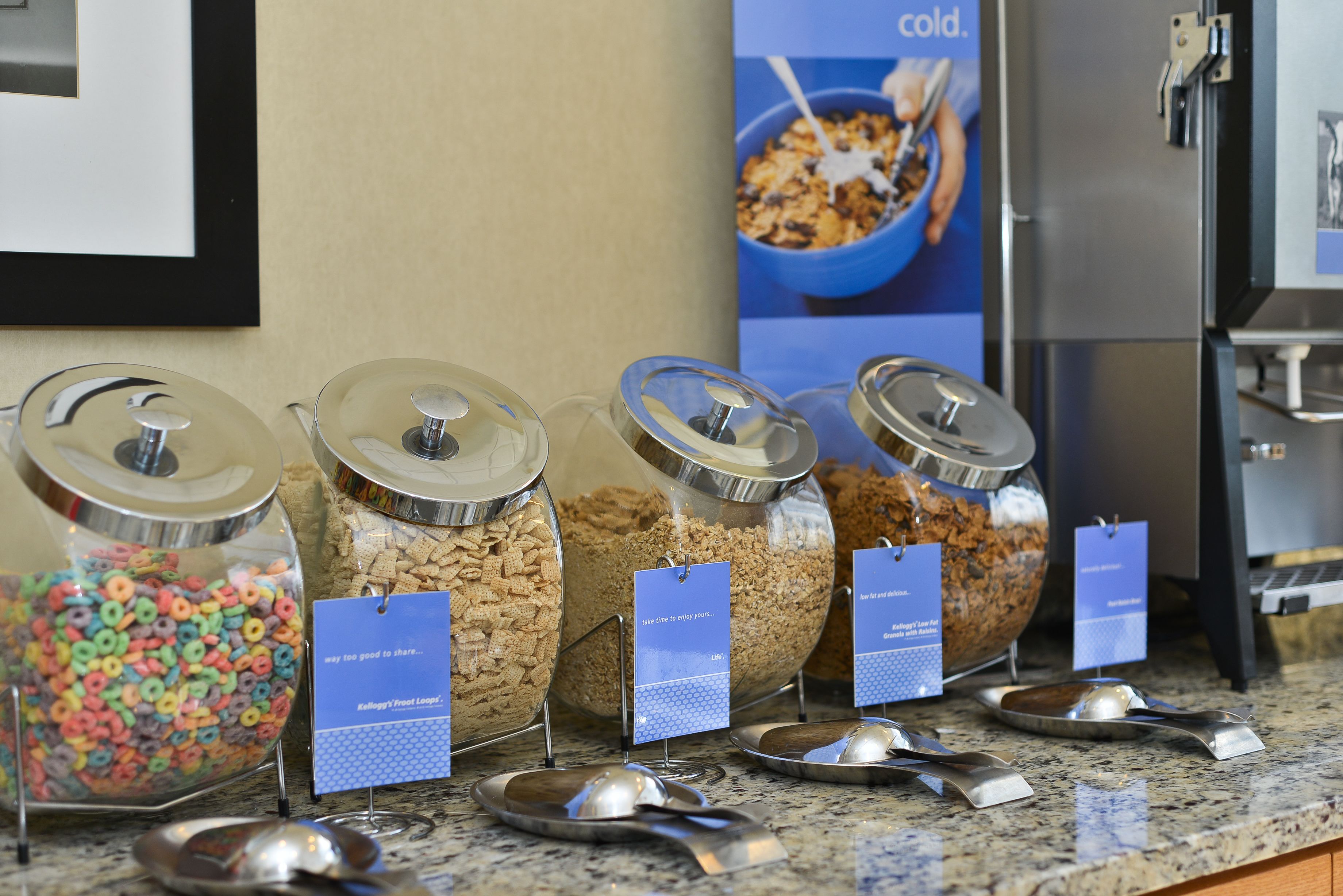 A breakfast bar with various cereal options and spoons.
