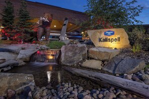 A hotel sign with a bear sculpture and a small waterfall.