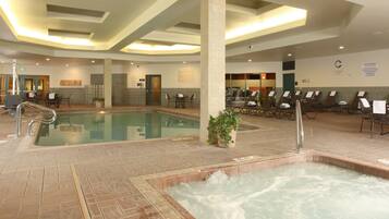 A large indoor swimming pool with multiple seating areas and a separate hot tub section.