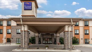 A Sleep Inn & Suites building with a covered entrance, stone facade, and a clear sky. - Sleep Inn & Suites Miles City I-94 (Miles City)