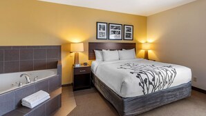 A hotel room with a large bed, a separate bathroom with a bathtub, two bedside lamps, and three framed pictures on the wall. - Sleep Inn & Suites Miles City I-94 (Miles City)
