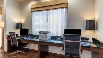 Un espacio de oficina moderno con dos escritorios, cada uno con computadora, impresora y silla.