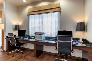 Un espacio de oficina moderno con dos escritorios, cada uno con computadora, impresora y silla.